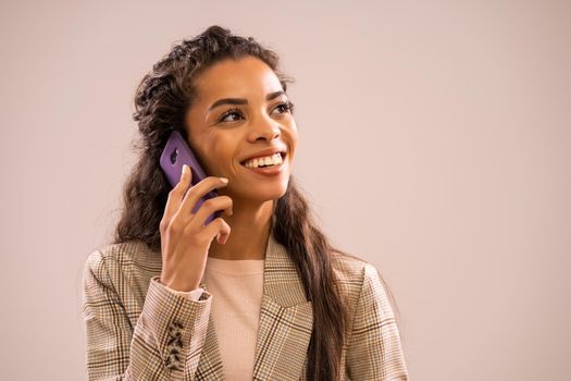 Studio shot portrait of beautiful happy african-american ethnicity businesswoman talking on phone.