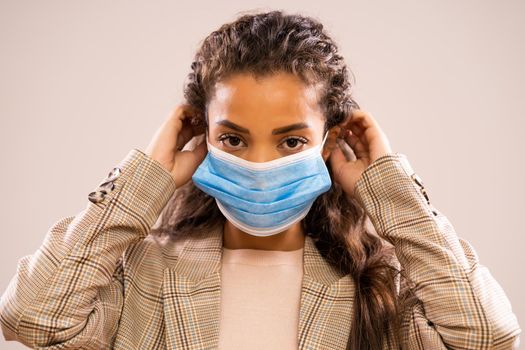 Studio shot portrait of beautiful african-american ethnicity businesswoman wearing protective mask.