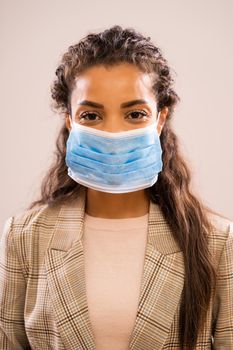 Studio shot portrait of beautiful african-american ethnicity businesswoman wearing protective mask.