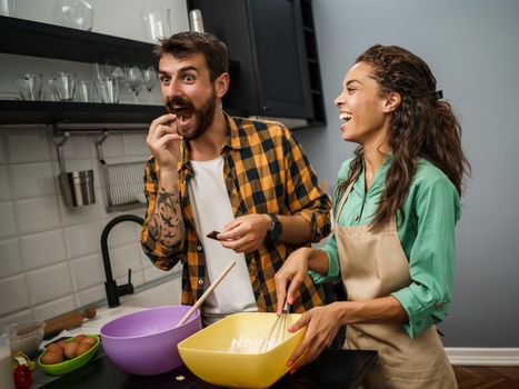 Happy multiracial couple cooking in their kitchen. They are making cookies and having fun.