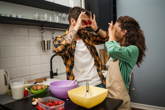 Happy multiracial couple cooking in their kitchen. They are making cookies and having fun.