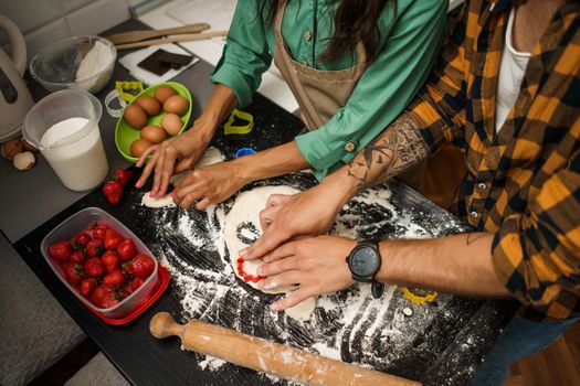 Close-up of multiracial couple making cookies in their kitchen.