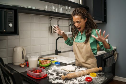 Young african-american woman is making cookies in her kitchen. She is tired of cooking.
