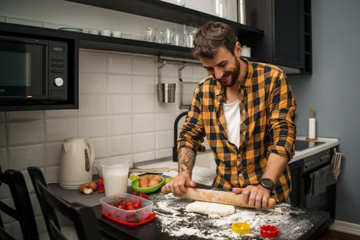 Young happy man is making cookies in his kitchen.