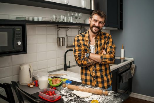 Young happy man is making cookies in his kitchen.