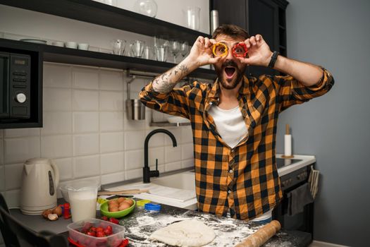 Young happy man is making cookies in his kitchen.