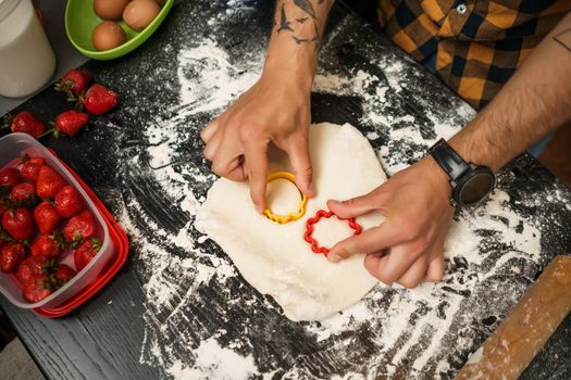 Close up image of young man who is making cookies in his kitchen.