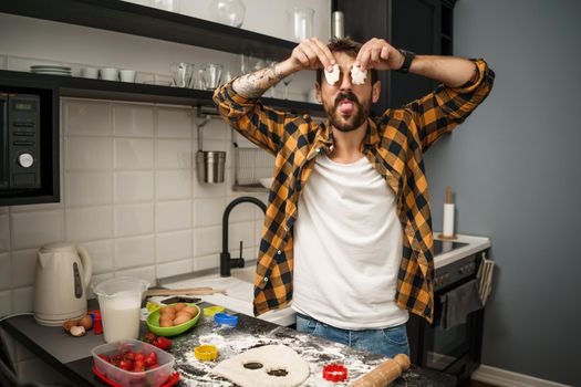 Young man is having fun while making cookies in his kitchen.