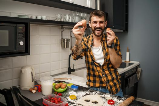 Young man is having fun while making cookies in his kitchen.