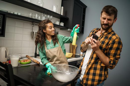 Young multiracial couple is cleaning their kitchen. They are arguing.