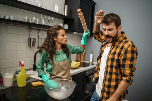 Young multiracial couple is cleaning their kitchen. They are arguing.