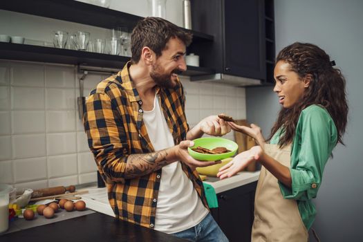 Multiracial couple is unhappy because cookies they have made are burnt.