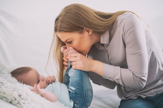 Happy mother and her baby boy playing at home.