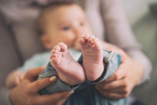 Close up image of baby feet. Mother is holding feet of her baby boy.