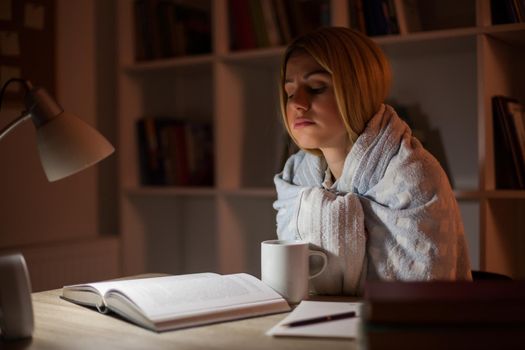 Student has to learn despite illness. She is covered in blanket.