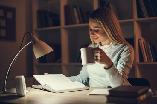 Student learning at home. She is drinking coffee to stay awake.