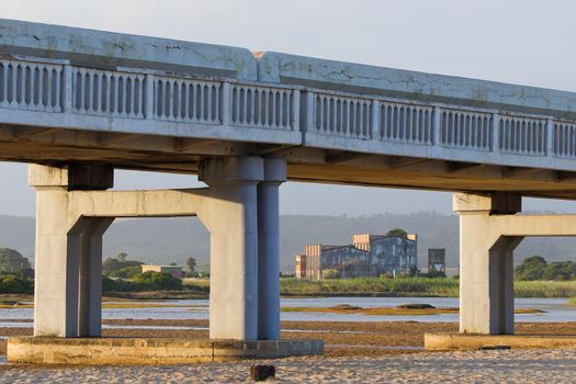 Old concrete bridge crossing over coastal sandbank with abandoned factory, Mossel Bay, South Africa