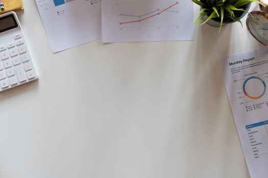 Top view hand of accountant using calculator on workplace with copy space, calculator and plant potted on white desk background, Accounting workplace concept.