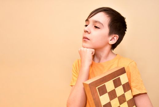 boy holds a chessboard in his hands and dreams and thinks about the game. free space for text.