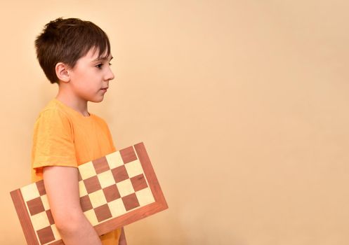 boy holds a chessboard in his hands and dreams and thinks about the game. free space for text.