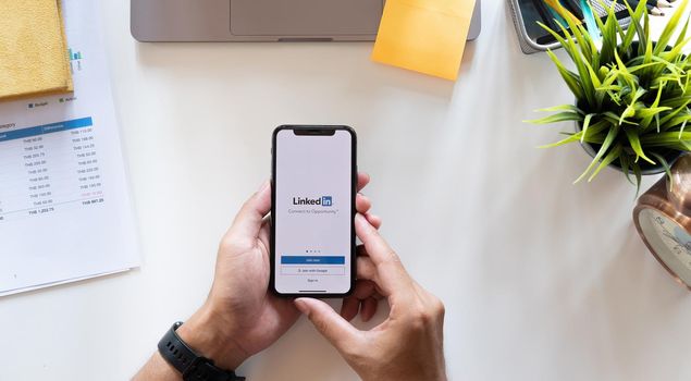 CHIANG MAI, THAILAND, APR 15, 2021 : A man holds Apple iPhone Xs with LinkedIn application on the screen.LinkedIn is a photo-sharing app for smartphones.