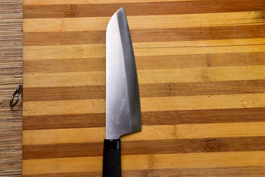 Cutting board and a kitchen knife on wooden background. Top view.