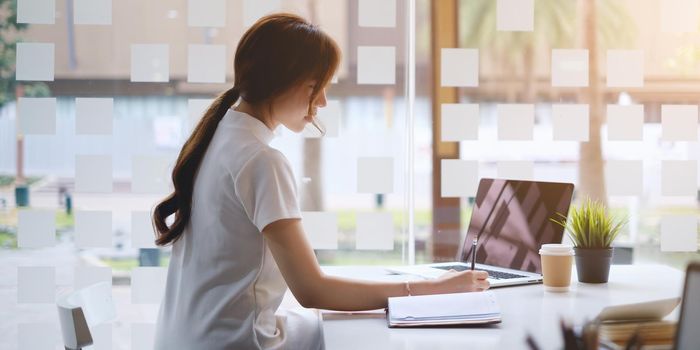 Casual business woman writing on notebook in home office. Business planning, tax, account, financial concept