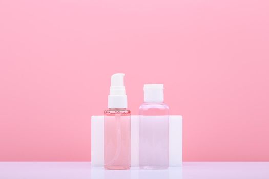 Cleaning gel or foam for face washing and cleansing and exfoliating lotion in transparent tubes against pink background with copy space. Concept of products for make up removing and skin cleaning