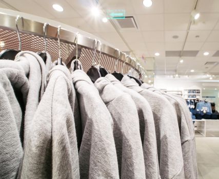 Gray sweatshirts or hoodies on hang in shopping department store for shopping, business fashion and advertisement concept. Copy space for text.