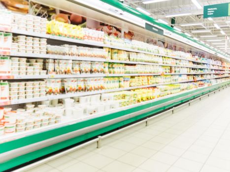 Abstract blurred supermarket aisle with colorful shelves and unrecognizable customers as background