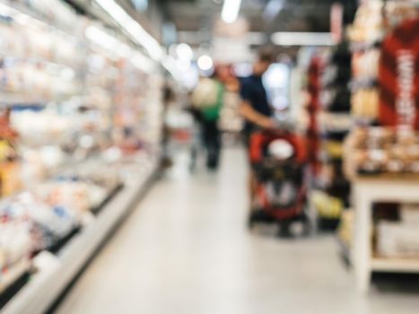 Abstract blurred supermarket aisle with colorful shelves and unrecognizable customers as background