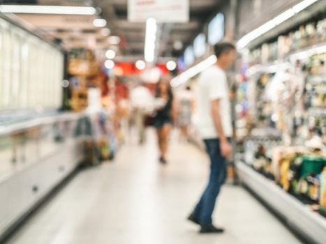 Abstract blurred supermarket aisle with colorful shelves and unrecognizable customers as background