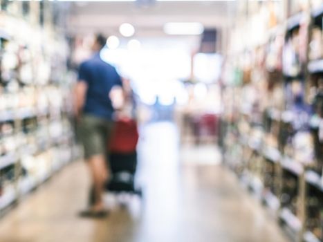 Abstract blurred supermarket aisle with colorful shelves and unrecognizable customers as background