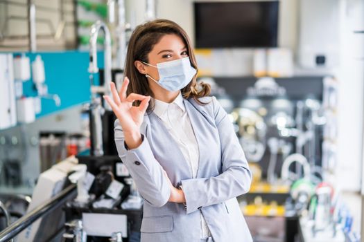 Confident businesswoman standing in her store. Small business owner posing in her store, wearing protective face mask.