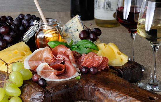 Antipasto catering platter with jerky bacon,  prosciutto, salami, cheese    and grapes on a wooden background