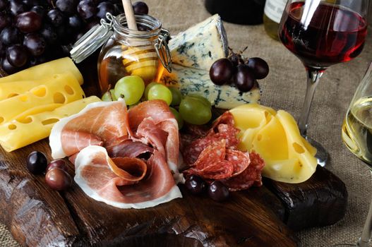 Antipasto catering platter with jerky bacon,  prosciutto, salami, cheese    and grapes on a wooden background