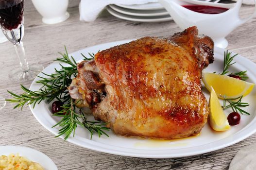Baked turkey thigh, on the table with cranberry sauce 