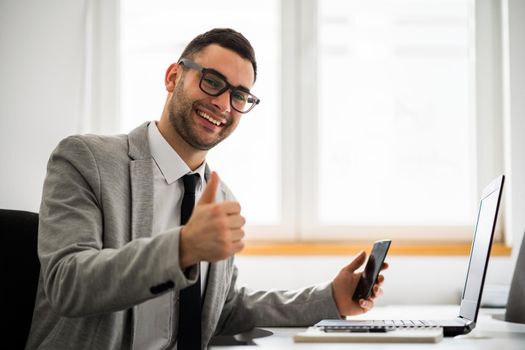 Young happy businessman is working in office.