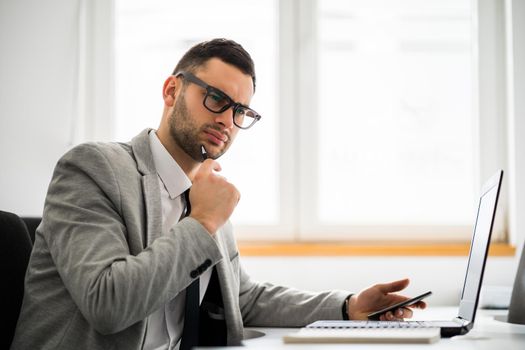 Young businessman is working in office. He is pensive.