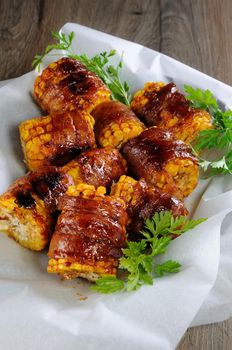 Grilled corn wrapped with bacon slices under BBQ sauce