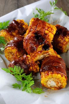 Grilled corn wrapped with bacon slices under BBQ sauce