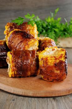 Grilled corn wrapped with bacon slices under BBQ sauce