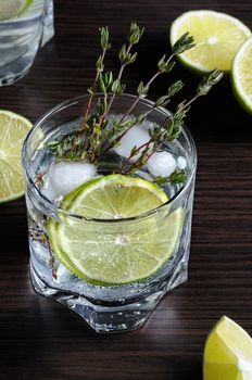 Cocktail with white rum and tonic, a slice of lime and thyme