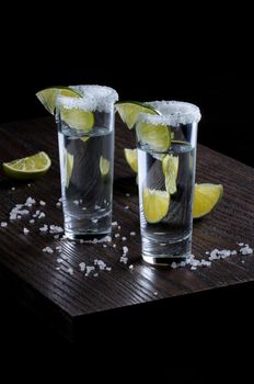 Portion of tequila, framed with a salt edge with slice lime in tall shot glasses