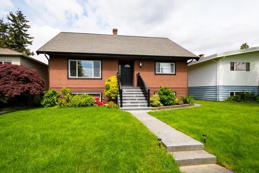 A perfect neighborhood. Average brown residential house built on land terrace with concrete stairway to the entrance