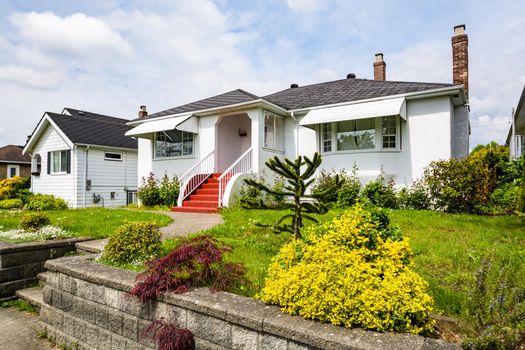 Main entrance of residential house with concrete pathway over green lawn on the front yard on cloudy day