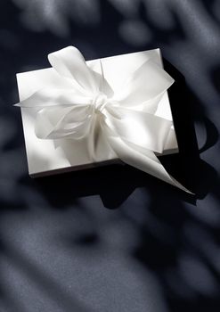 Anniversary celebration, shop sale promotion and luxe surprise concept - Luxury holiday white gift box with silk ribbon and bow on black background, luxe wedding or birthday present