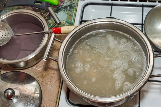 A large saucepan of simmering broth on a white stovetop. View from above