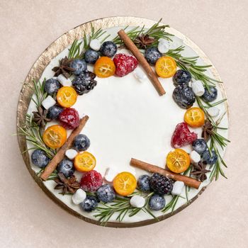 The round cake is decorated with berries and fruits. Square shot close up top view