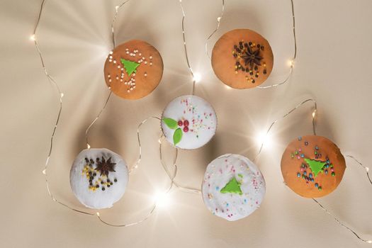 Muffins on a light background decorated for New Year and Christmas with a glowing garland, top view